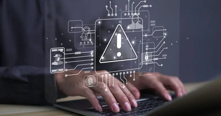 Hands typing on a laptop with a virtual overlay displaying cybersecurity icons, including a warning symbol, padlock, fingerprint, and person with a hat, representing potential cyber threats and security measures to speak to the importance of the latest SAP S/4HANA upgrade
