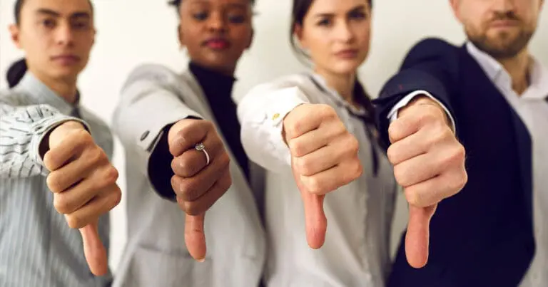 four serious looking professionals standing in a row each giving a thumbs down to the camera